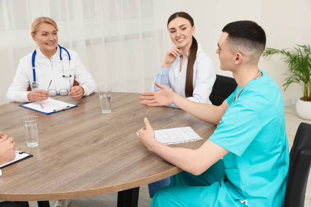 Medical conference. Team of doctors having discussion at wooden table in clinic - 写真・画像