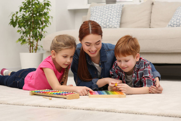 Happy mother and children playing with different math game kits on floor in room. Study mathematics with pleasure - Foto, Imagem