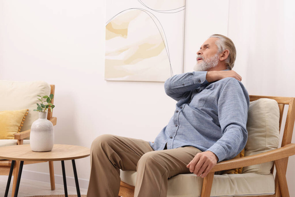 Senior man suffering from pain in his shoulder at home. Arthritis symptoms - Valokuva, kuva