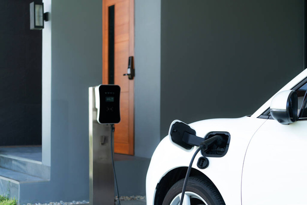 Progressive concept of EV car and home charging station powered by sustainable and clean energy with zero CO2 emission for green environmental. Charging point at residential area for electric vehicle. - 写真・画像