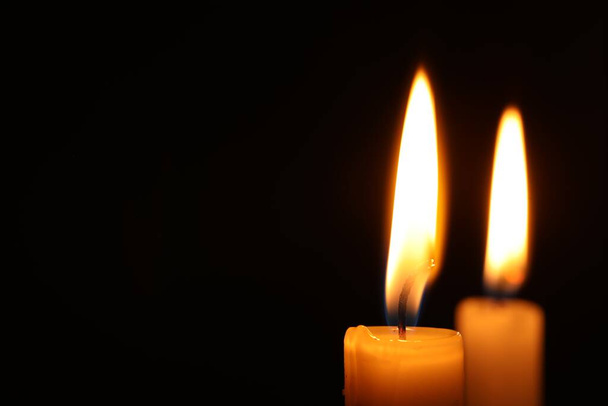 Burning candles on black background, closeup. Space for text - Foto, Bild