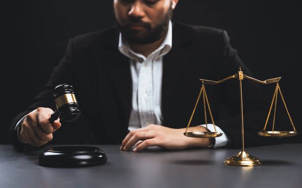 Focus symbols of justice, gavel hammer and scale balance on blurred background of thoughtful lawyer or judge sitting at his desk for integrity and fairness of the legal system. equility - 写真・画像
