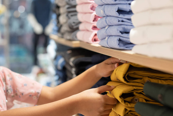 Valikoiva painopiste vaatteita järjestetty telineet ja ihmisen käsi ostoskeskuksessa - Valokuva, kuva