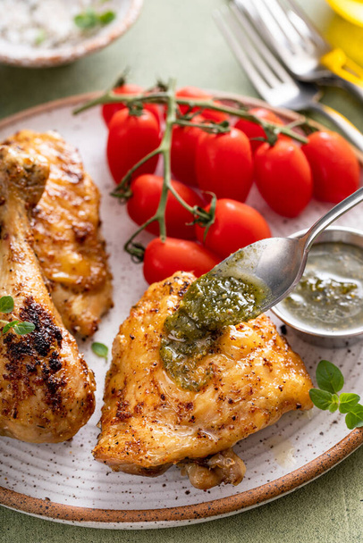 Roasted lemon and herb chicken drumsticks and thighs served with pesto sauce - Photo, image