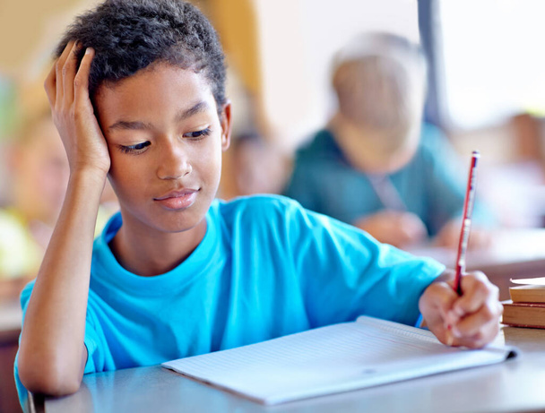 Διαβάζει σκληρά. Ένα νεαρό αγόρι κρατάει σημειώσεις ενώ κάθεται στην τάξη. - Φωτογραφία, εικόνα