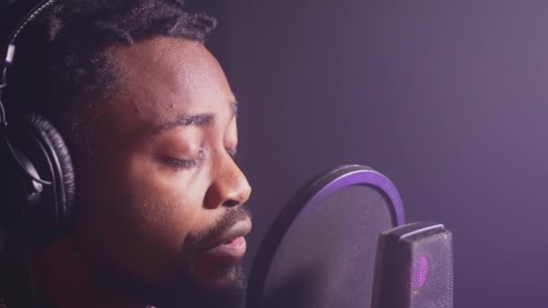tehetséges afro-amerikai énekes énekel új dalt audio stúdió, closeup portré, jóképű fekete férfi professzionális fejhallgató és mikrofon, így új album pop dalok - Felvétel, videó