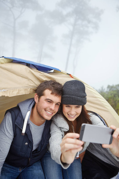 Bir açık hava macerasının ekran görüntüsü. Genç bir çift çadırda otururken kendi fotoğraflarını çekiyor. - Fotoğraf, Görsel