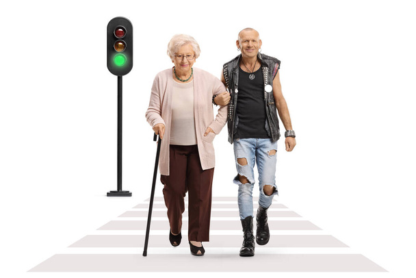 Punk man helping a senior woman with a walking cane crossing a street isolated on white background - Photo, Image