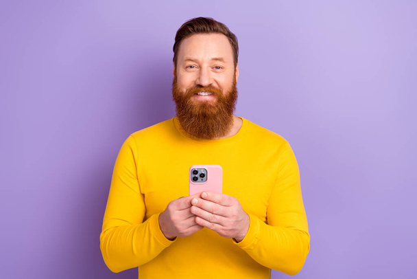 Photo of young satisfied business influencer blogger hold smartphone review new apple gadgets youtube isolated on violet color background. - Valokuva, kuva