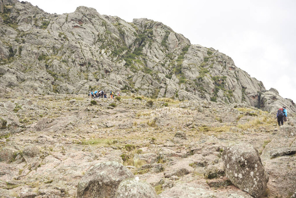 Лос Гигантес, Кордова, Аргентина, 6 апреля 2023 года: группа альпинистов поднимается по тропе посреди скалистого горного ландшафта, идеального туристического направления для походов и восхождений. - Фото, изображение