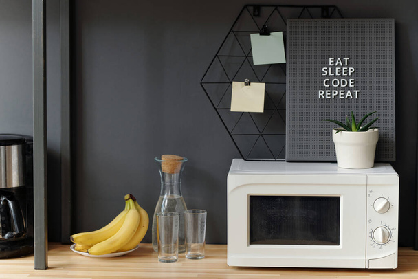Moderni elettrodomestici da cucina con frutta e barattolo con acqua sul tavolo in cucina ufficio - Foto, immagini