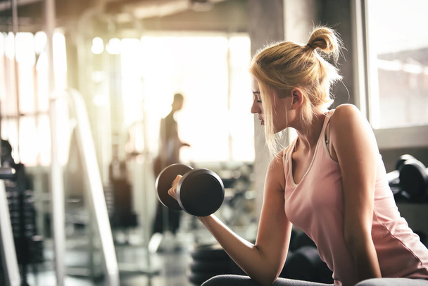 Sport Woman Lifting Hanteln und Workout-Übungen im Fitnessstudio - Lifestyle- und Gesundheitskonzept - Foto, Bild