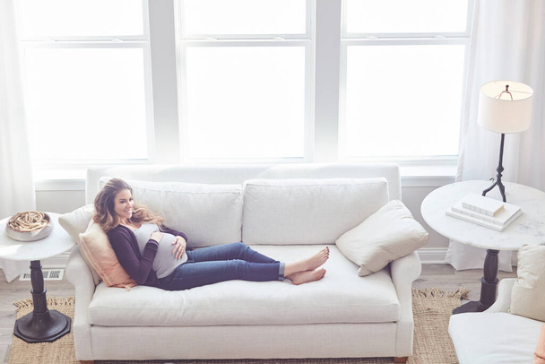 Bebeğin iyiliği için dinleniyorum sadece. Çekici, genç ve hamile bir kadının evdeki kanepede dinlenirken tam boy fotoğrafı. - Fotoğraf, Görsel