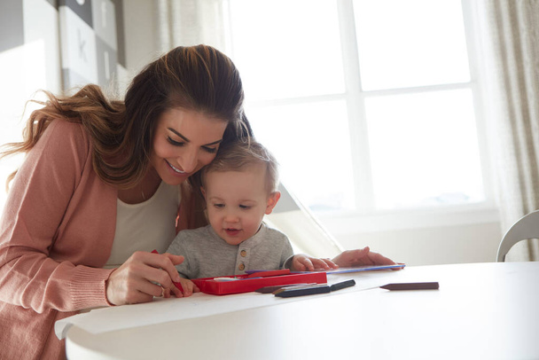 Aprenden a través del juego. una mujer y su hijo pequeño usando lápices de colores para dibujar en casa - Foto, Imagen