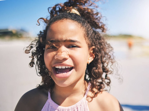 Child, beach and portrait in nature with a young girl and smile on summer holiday. Face, closeup and African female child at the sea on vacation feeling happy from the ocean and outdoor fun in sun. - Fotografie, Obrázek