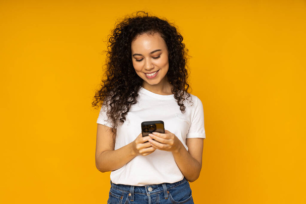 Young woman with phone on yellow background - Fotoğraf, Görsel