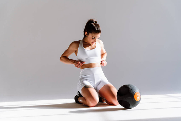 Young female athlete training in a gym using sport equipment. Fit woman working out . Concept about fitness, wellness and sport preparation. - Foto, afbeelding
