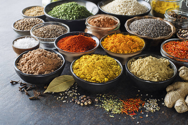 Colorful herbs and spices for cooking meal. Indian and Asian spices On grey stone background closeup - Fotó, kép