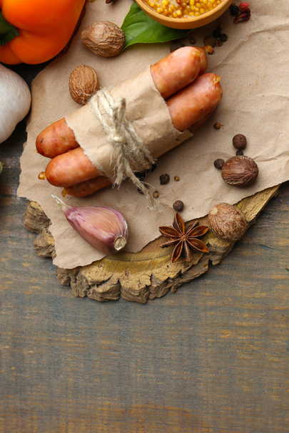 Composition of thin sausages, mustard in bowl and spices on wooden background - Фото, зображення