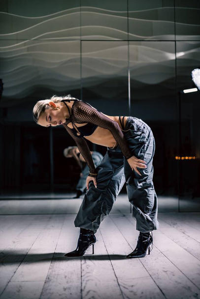 A vertical shot of a beautiful female dancer posing in mesh overlay crop top in black and baggy pants - 写真・画像