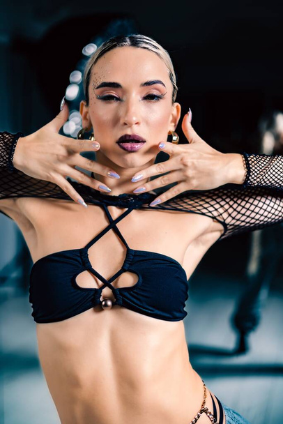 A vertical shot of a beautiful female dancer posing in mesh overlay crop top in black - 写真・画像