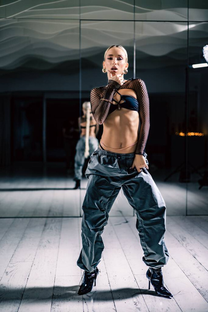 A vertical shot of a beautiful female dancer posing in mesh overlay crop top in black and baggy pants - Foto, afbeelding