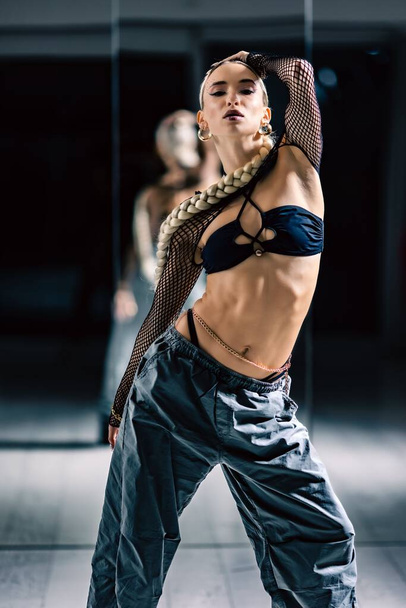A vertical shot of a beautiful female dancer posing in mesh overlay crop top in black and baggy pants - Fotoğraf, Görsel