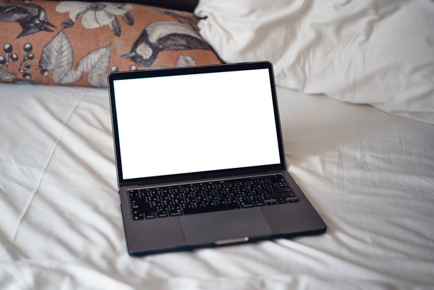 Blanke vrouw ligt op bed met behulp van laptop, laptop op leeg bed - Foto, afbeelding