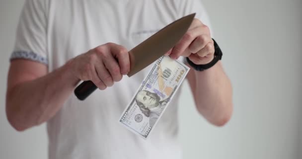 Mies leikkaa dollarin setelin terävällä veitsellä lähikuva 4k elokuva hidastettuna. Konkurssi- ja finanssikriisin käsite - Materiaali, video