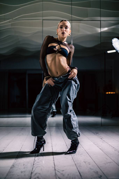 A vertical shot of a beautiful female dancer posing in mesh overlay crop top in black and baggy pants - Photo, Image