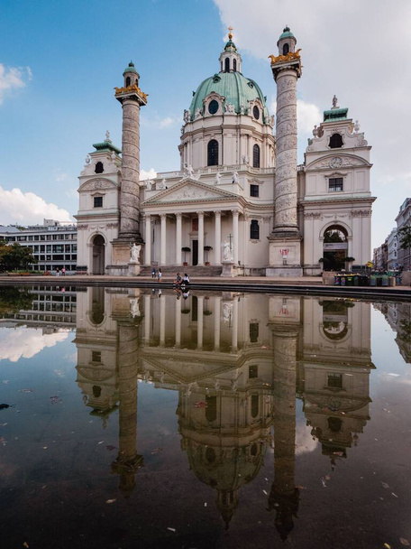 A vertical shot of the Karlskirche church near the water in Karlsplatz in Vienna, Austria - 写真・画像