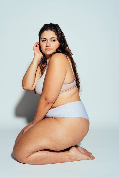 Plus size woman posing in studio in lingerie. Model on white background. Hard light studio shot - Foto, afbeelding