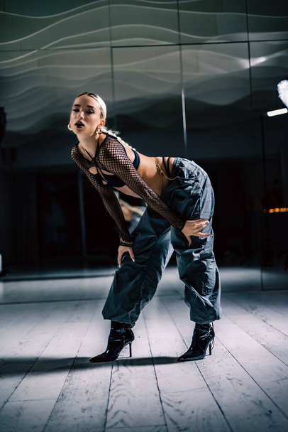 A vertical shot of a beautiful female dancer posing in mesh overlay crop top in black and baggy pants - Foto, Imagem