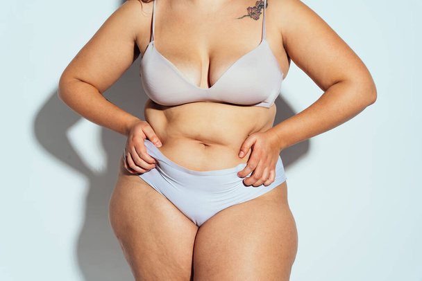 Plus size woman posing in studio in lingerie. Model on white background. Hard light studio shot - Foto, Imagen