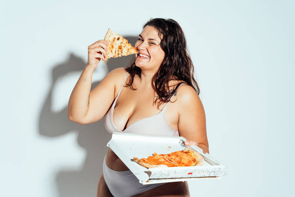 Plus size woman posing in studio in lingerie. Model on white background. Hard light studio shot - 写真・画像
