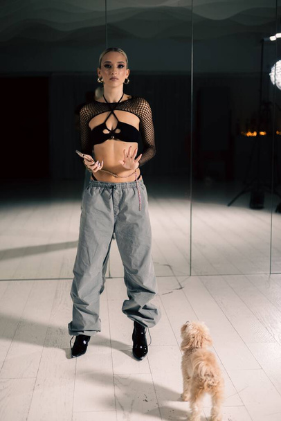 A vertical shot of a beautiful female dancer posing in mesh overlay crop top in black and baggy pants - Photo, image