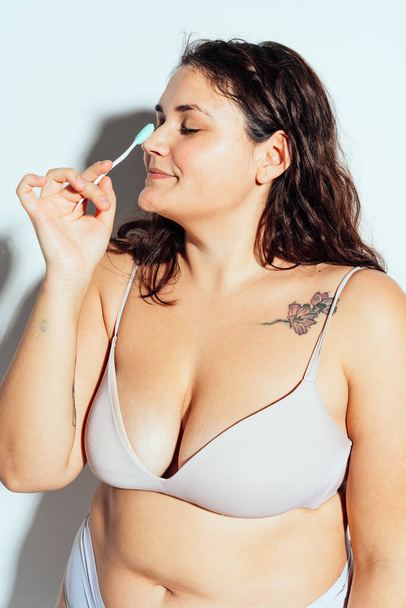Plus size woman posing in studio in lingerie. Model on white background. Hard light studio shot - Foto, Imagen