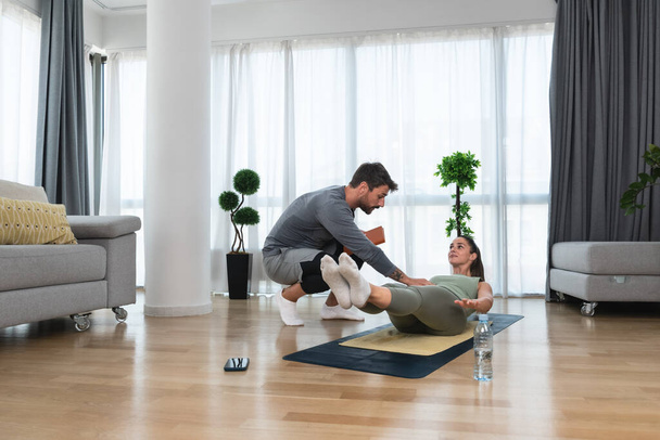 Woman with her personal fitness trainer. Couple exercising together. Man and woman in sports wear doing workout at home. Healthy lifestyle training with coach instructor for better life - Foto, afbeelding