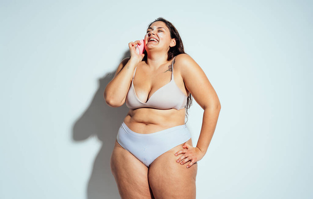 Plus size woman posing in studio in lingerie. Model on white background. Hard light studio shot - Foto, imagen