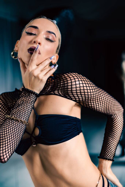 A vertical shot of a beautiful female dancer posing in mesh overlay crop top in black - Photo, Image