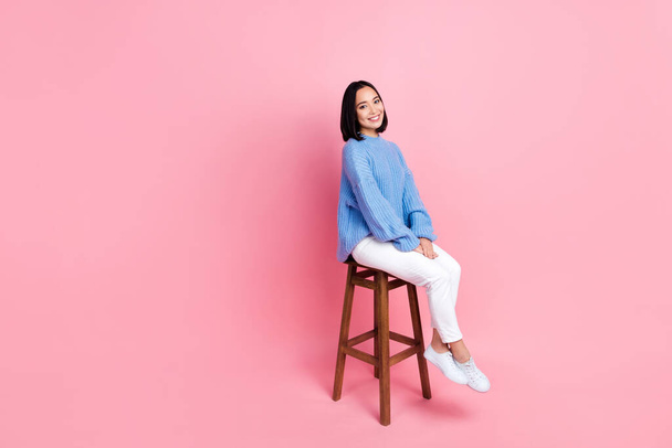 Full size photo of good mood satisfied nice woman dressed knit pullover trousers sitting on chair isolated on pink color background. - Zdjęcie, obraz