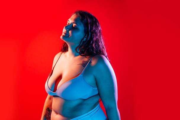 Plus size woman posing in studio in lingerie. Model on colored background. Hard light studio shot - Zdjęcie, obraz