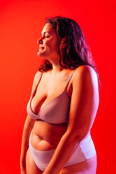 Plus size woman posing in studio in lingerie. Model on colored background. Hard light studio shot - Photo, image