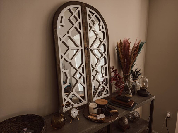 A unique ornate mirror with a wooden frame surrounded by different items. Cozy house decor. - Foto, afbeelding