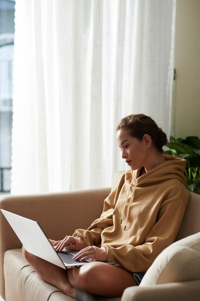 Серйозна молода жінка переглядає код програмування на екрані ноутбука при роботі з дому через пандемію коронавірусу
 - Фото, зображення