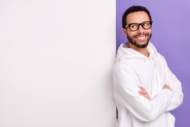 Photo of satisfied confident man wear white hoodie crossed arms glasses look paper placard promo offer isolated on violet color background. - Foto, Bild