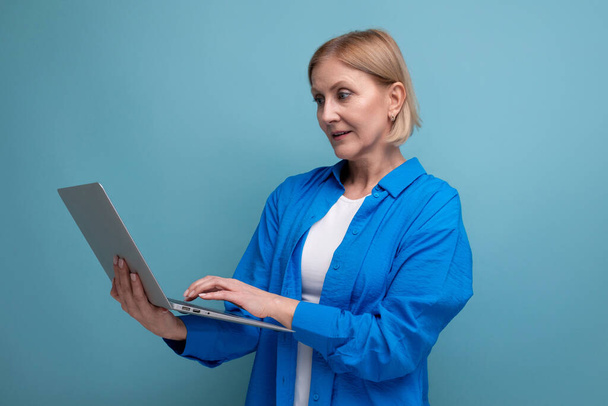 Başarılı yetişkin iş kadını mavi arkaplanda uzaktan bilgisayarla fotokopi alanı kullanarak çalışıyor.. - Fotoğraf, Görsel