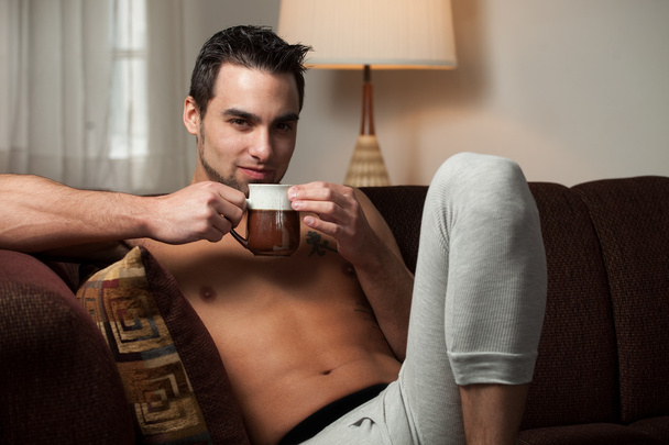 aantrekkelijke man ontspannen thuis in lange ondergoed. - Foto, afbeelding