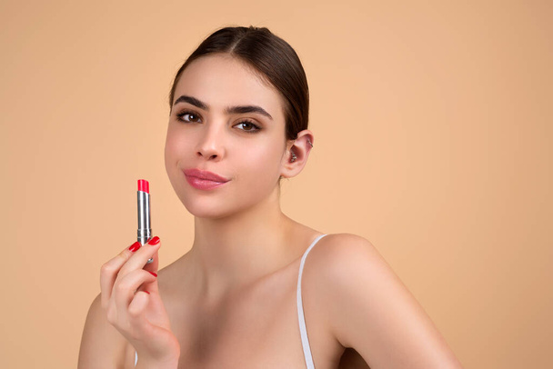 Photo of shirtless woman posing with lipstick, isolated studio background. Beautiful woman holding with naked shoulder hold lipstick. Sexy girl using lipstick - Foto, imagen