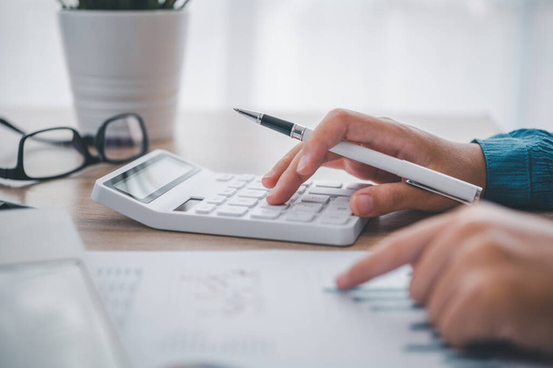 primer plano La persona de negocios está sentado en una calculadora con un gráfico en la oficina de contabilidad financiera concepto
 - Foto, Imagen